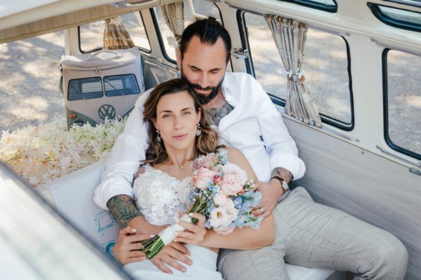 Foto von einem Brautpaar mit Hochzeitsstrauß im Auto nach einer Freien Trauung mit Katrin Nalobin, der erfahrenen Traurednerin.